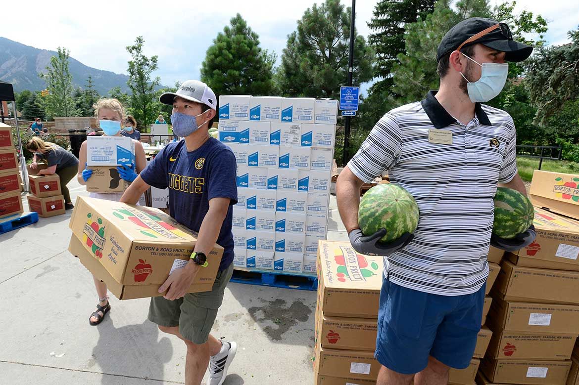 Voluntarios llevan cajas en una distribución de alimentos.