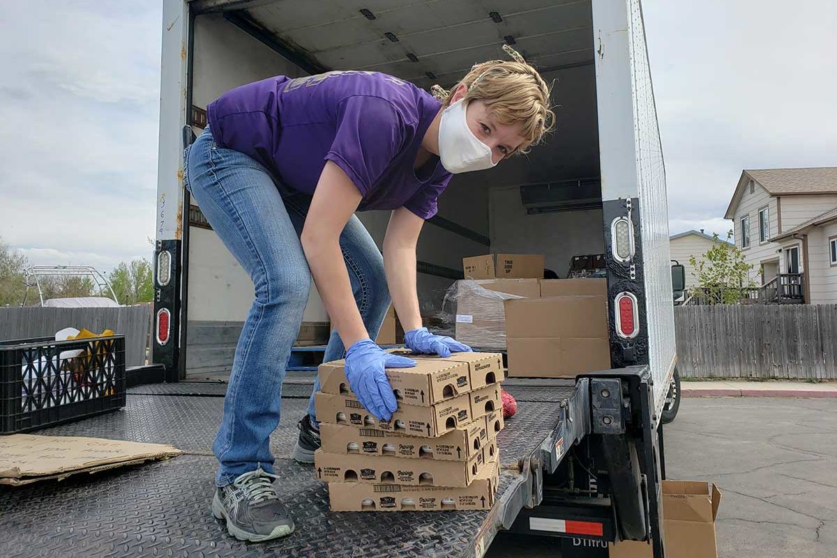 Una mujer baja cajas de comida de un camión