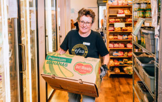 A volunteer carries a box of food in EFAA's food pantry