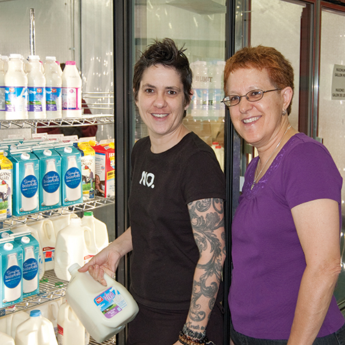 A woman with tattoos holds a gallon of milk at Feeding Families in 2004