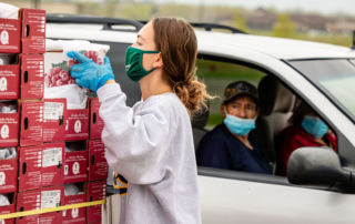 A college student grabs a box of grapes while a couple watches