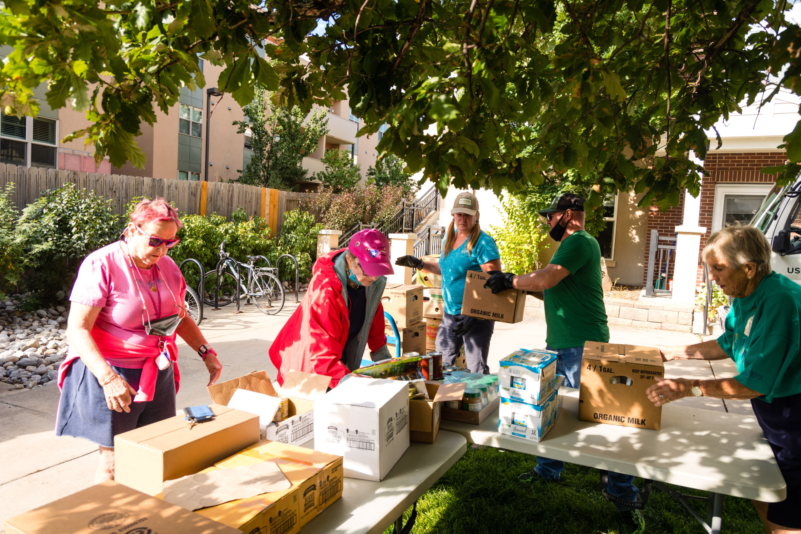A group of people surround a table with boxes of food on it