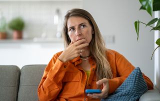 concerned woman thinking while holding phone